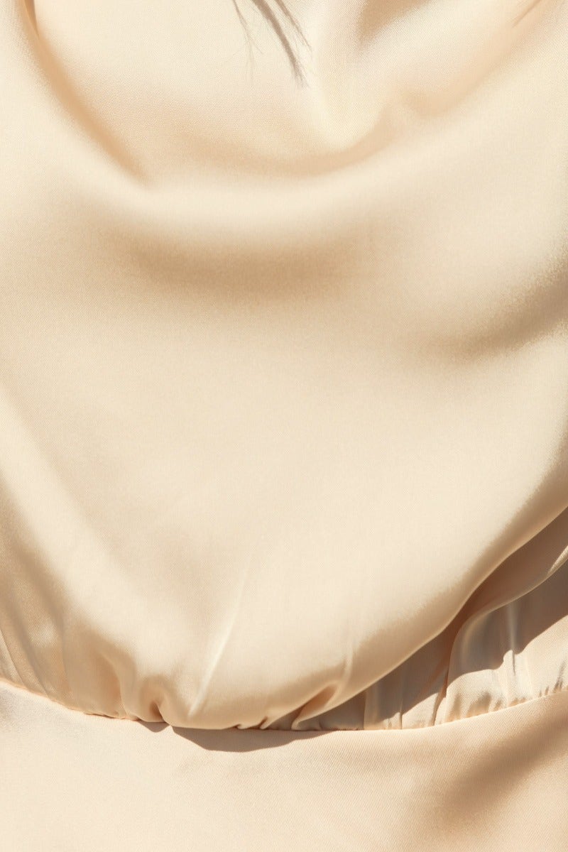 Close-up of the soft satin fabric of a Honeymoon Maxi Dress in a light beige color, showcasing its smooth texture.