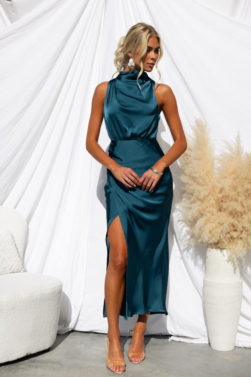 Teal satin maxi dress with high neckline and asymmetric hem, styled for a chic look.