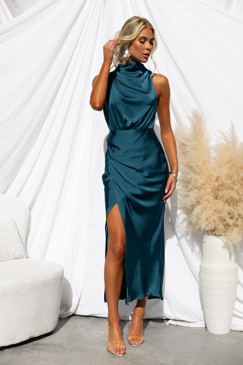 Teal satin Honeymoon maxi dress with asymmetric hemline and high neckline, styled for a chic look.