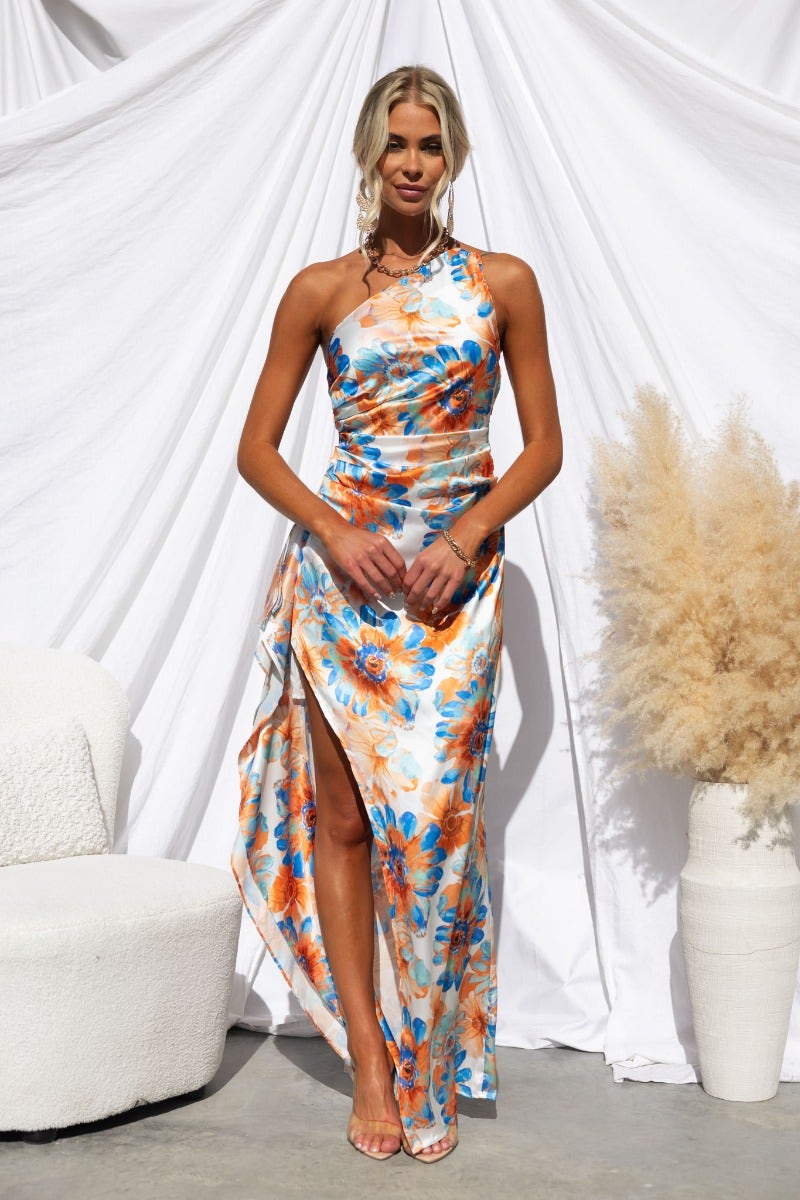 Model wearing a floral satin one-shoulder maxi dress with an asymmetrical hemline and ruffle trim.