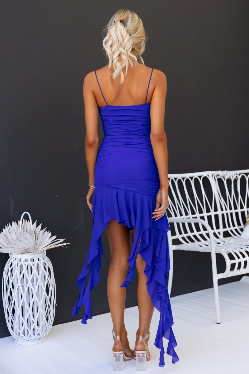 Back view of a blue midi dress with ruffled hem and spaghetti straps on a model.