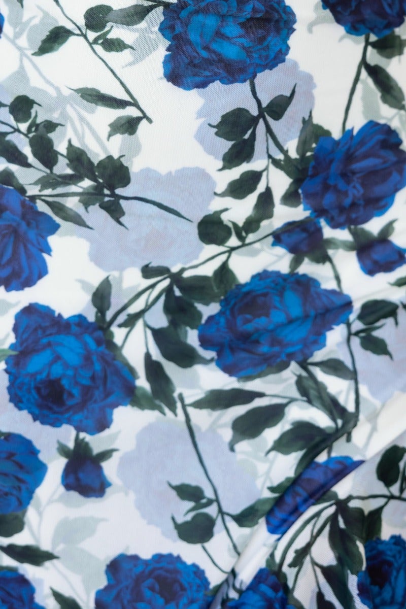 Close-up of floral print featuring blue roses and green leaves on a white background, perfect for a maxi dress.