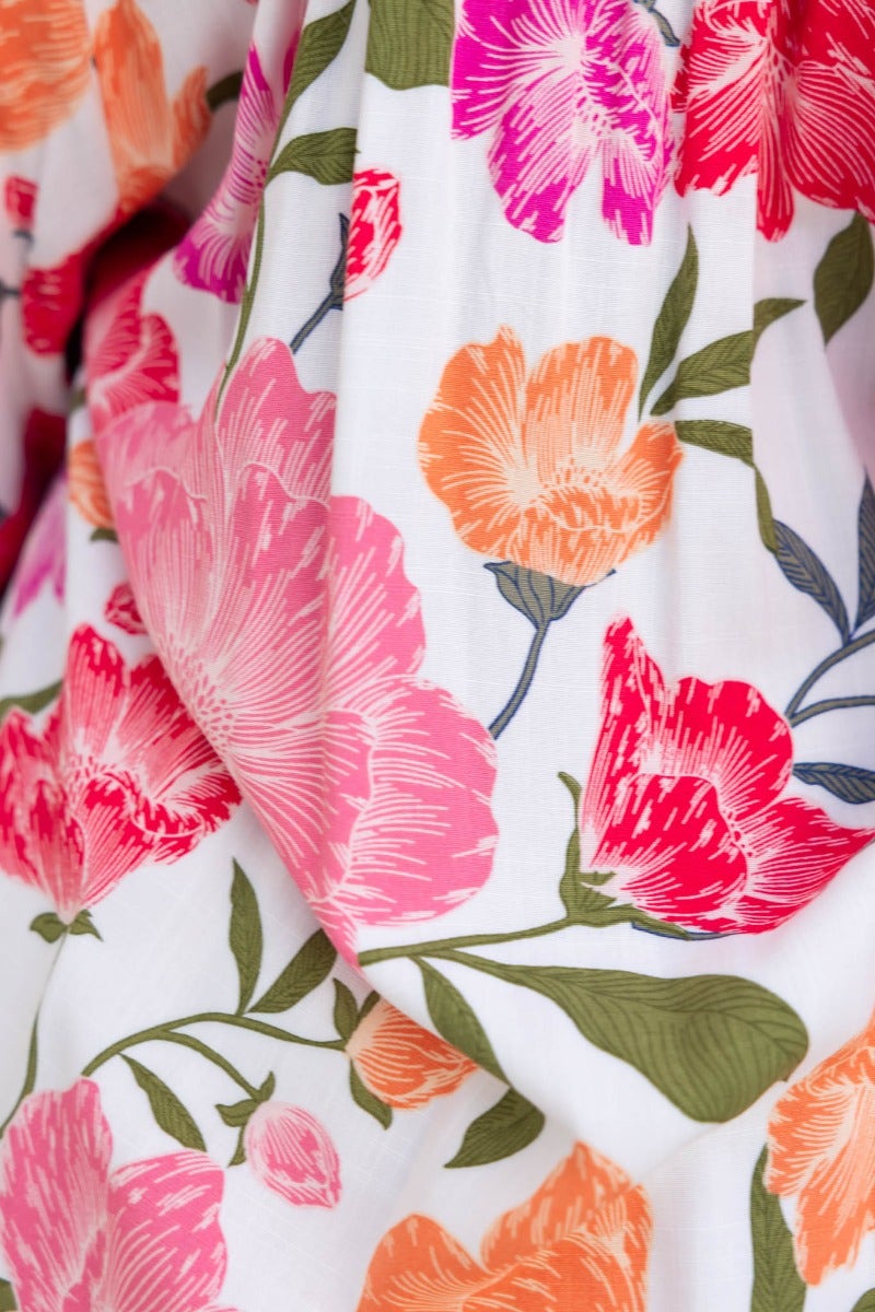 Close-up of vibrant floral print in pink, orange, and green on delicate fabric.