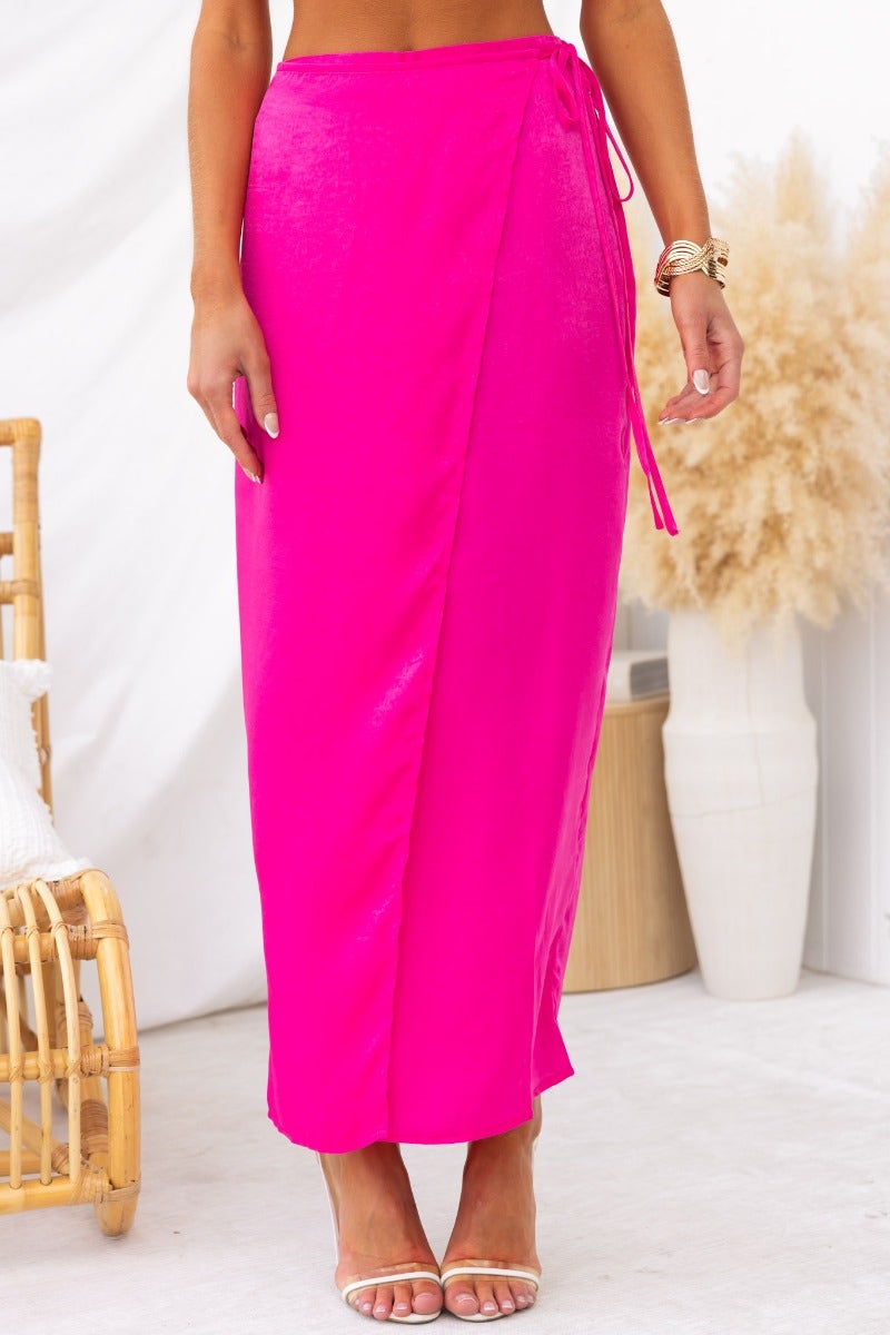 Model wearing vibrant pink Nerida Wrap Midi Skirt with fabric tie and asymmetric hem, showcasing stylish summer fashion.