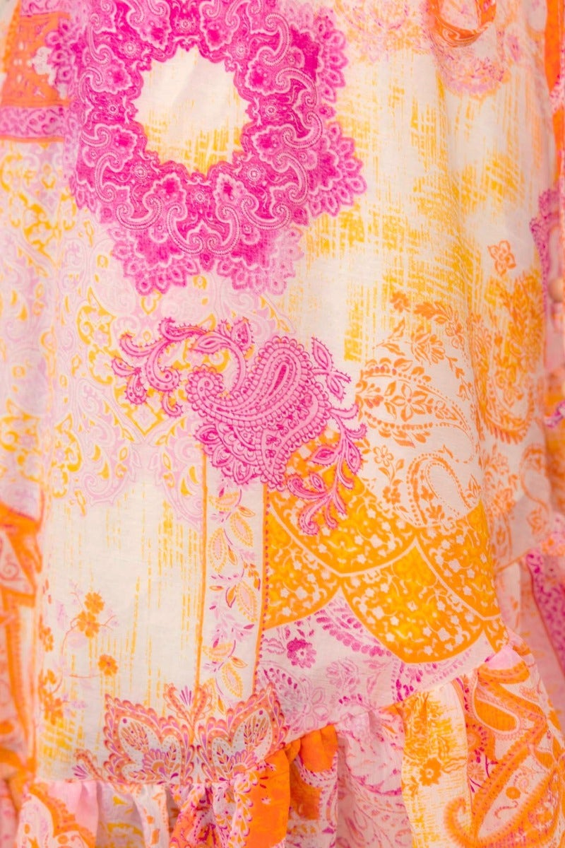 Close-up of Fools Gold Wrap Dress featuring vibrant pink and orange floral patterns with intricate designs.