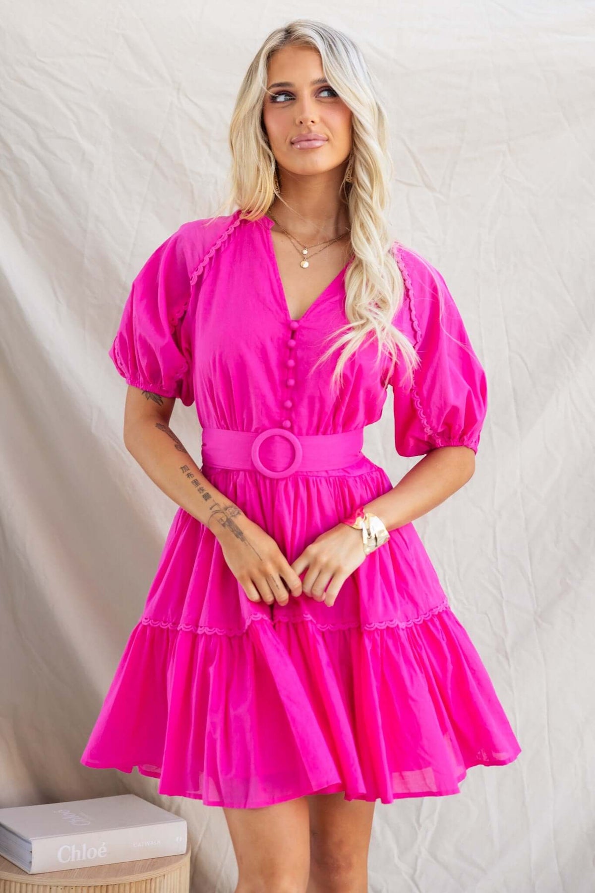 Bright pink Verlaine Dress with V-neckline, button-up bust, and puff sleeves for a stylish look.