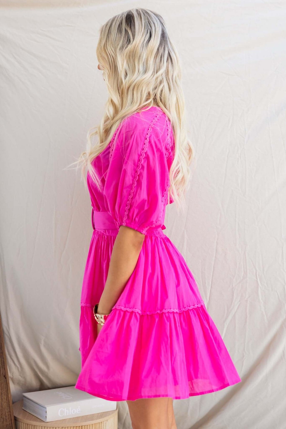 Side view of the Verlaine Dress in vibrant pink with a V-neckline, button-up bust and elastic sleeves, showcasing a playful style.