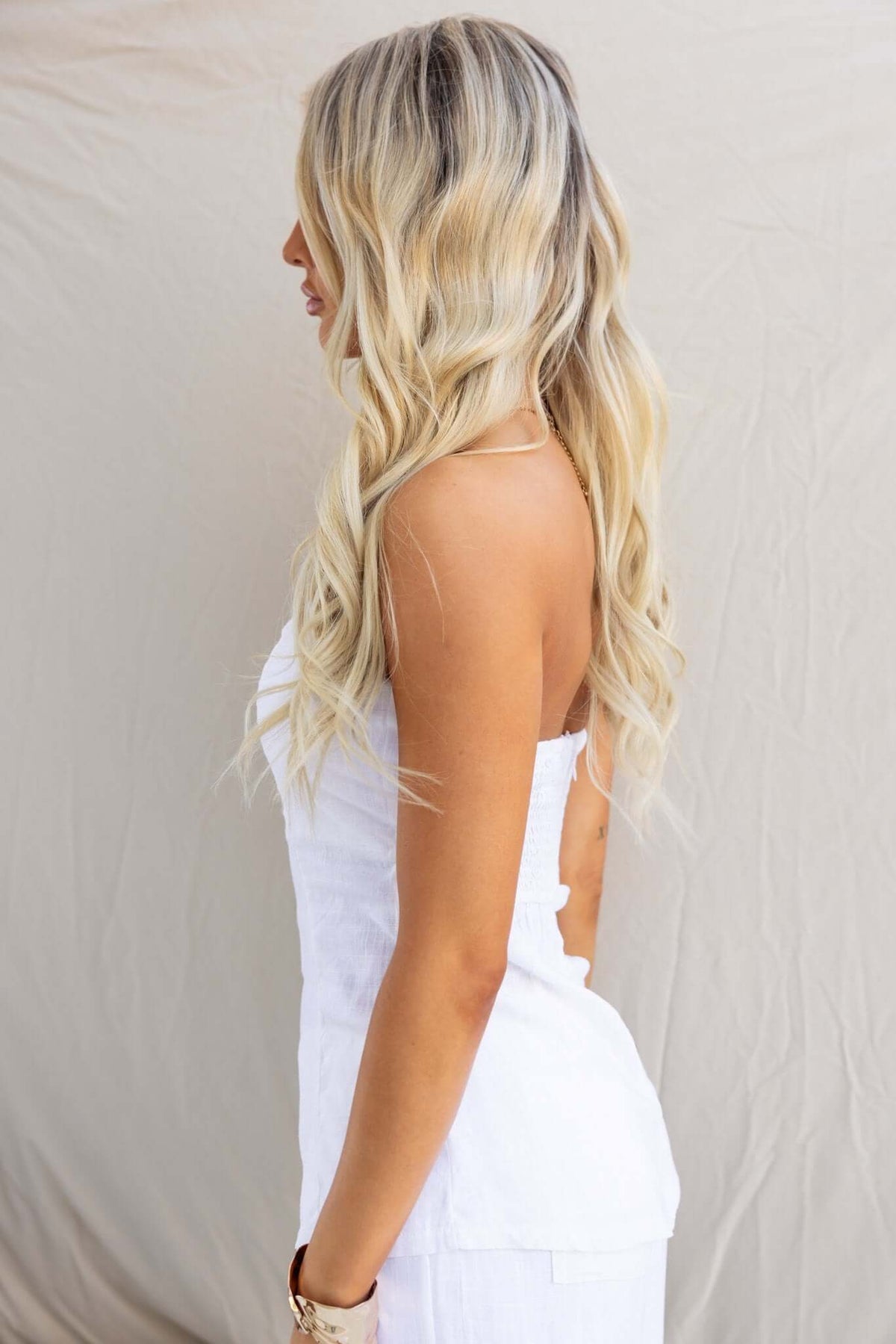 Profile view of a model wearing a strapless Irina Top in white, showcasing its elegant design and linen texture.