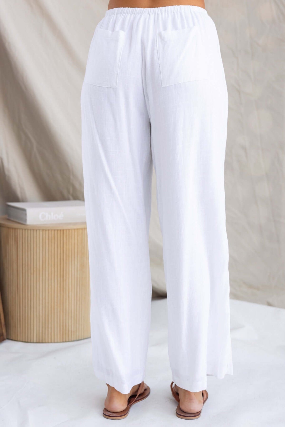 Back view of Irina Pants featuring an elastic waistband, pockets, and comfortable, flowy fit in white fabric.