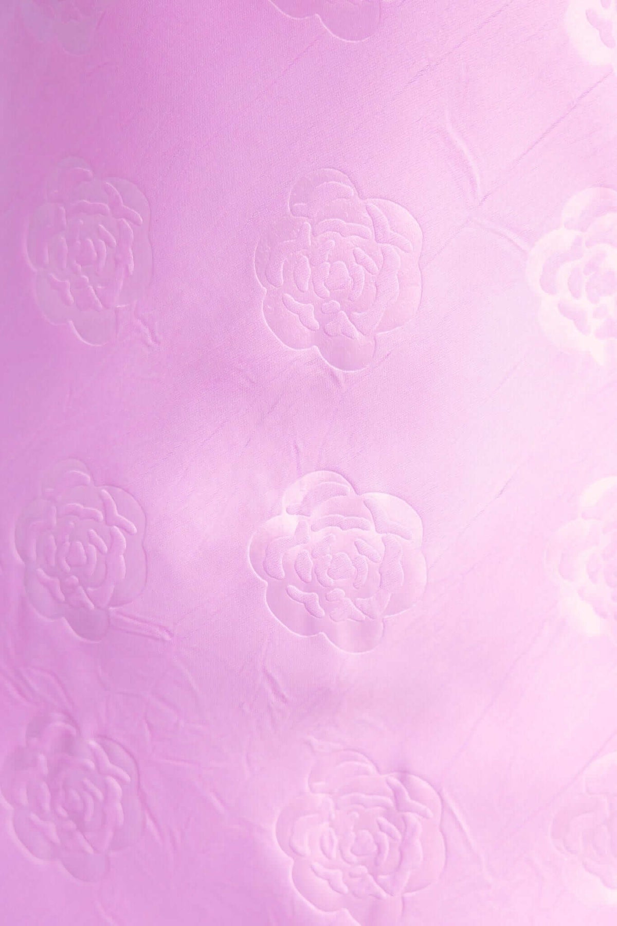 Close-up of textured pink fabric featuring embossed flower patterns, ideal for fashion and textile design.