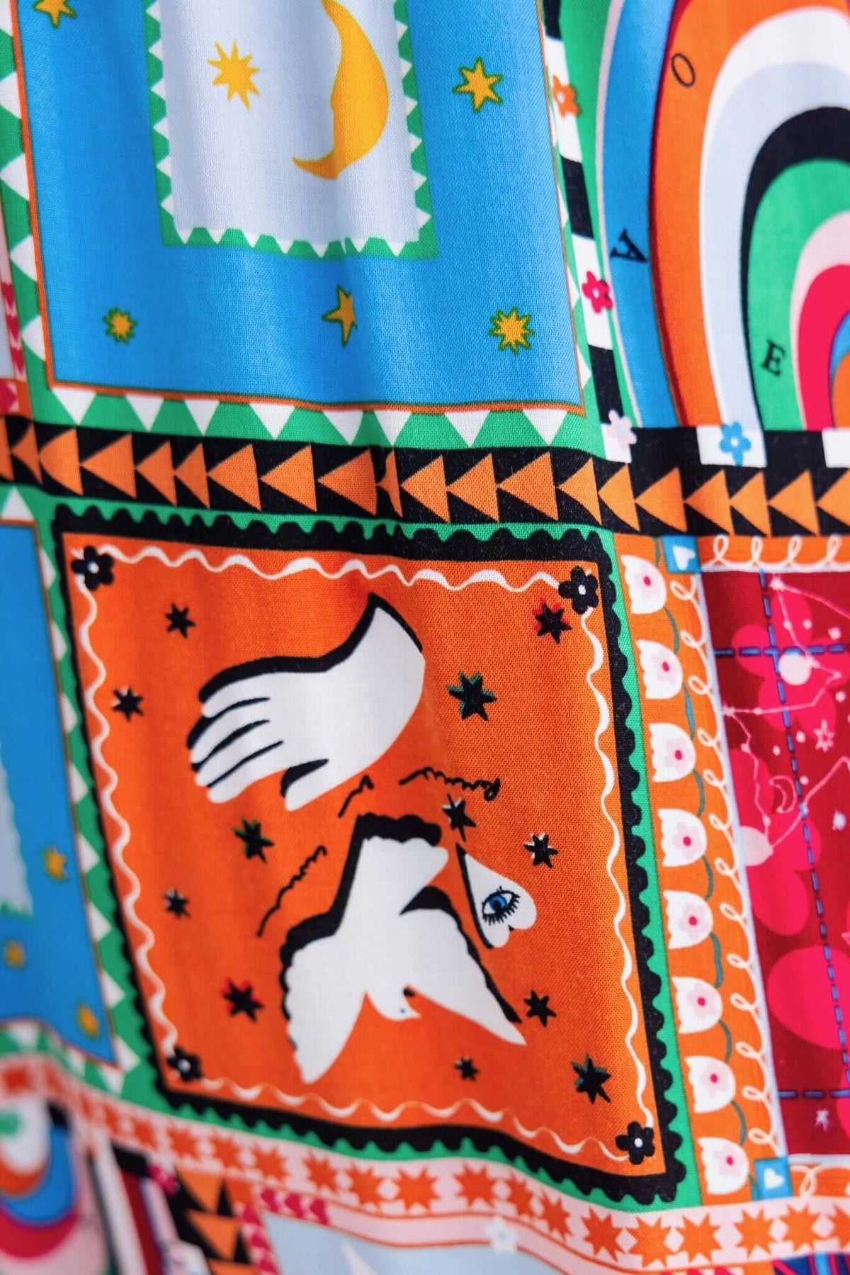 Colorful fabric pattern featuring bold graphics and designs in blue, orange, and pink, ideal for Maito Pants styling.