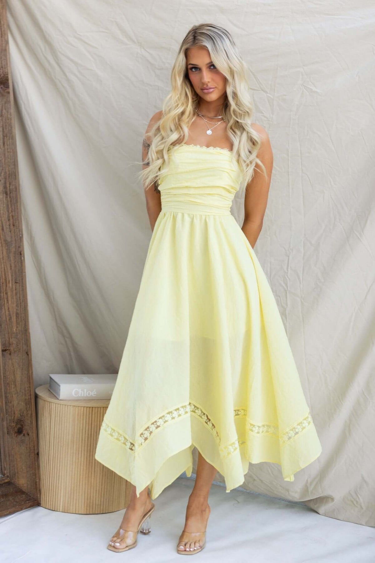 Civita Maxi Dress in soft yellow, strapless with handkerchief hem, styled by model against a neutral backdrop.
