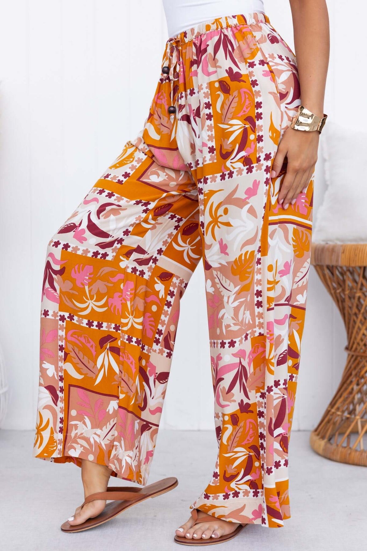 Valora Pants featuring a mid-high waist, elastic waistband, and vibrant floral print in warm colors.