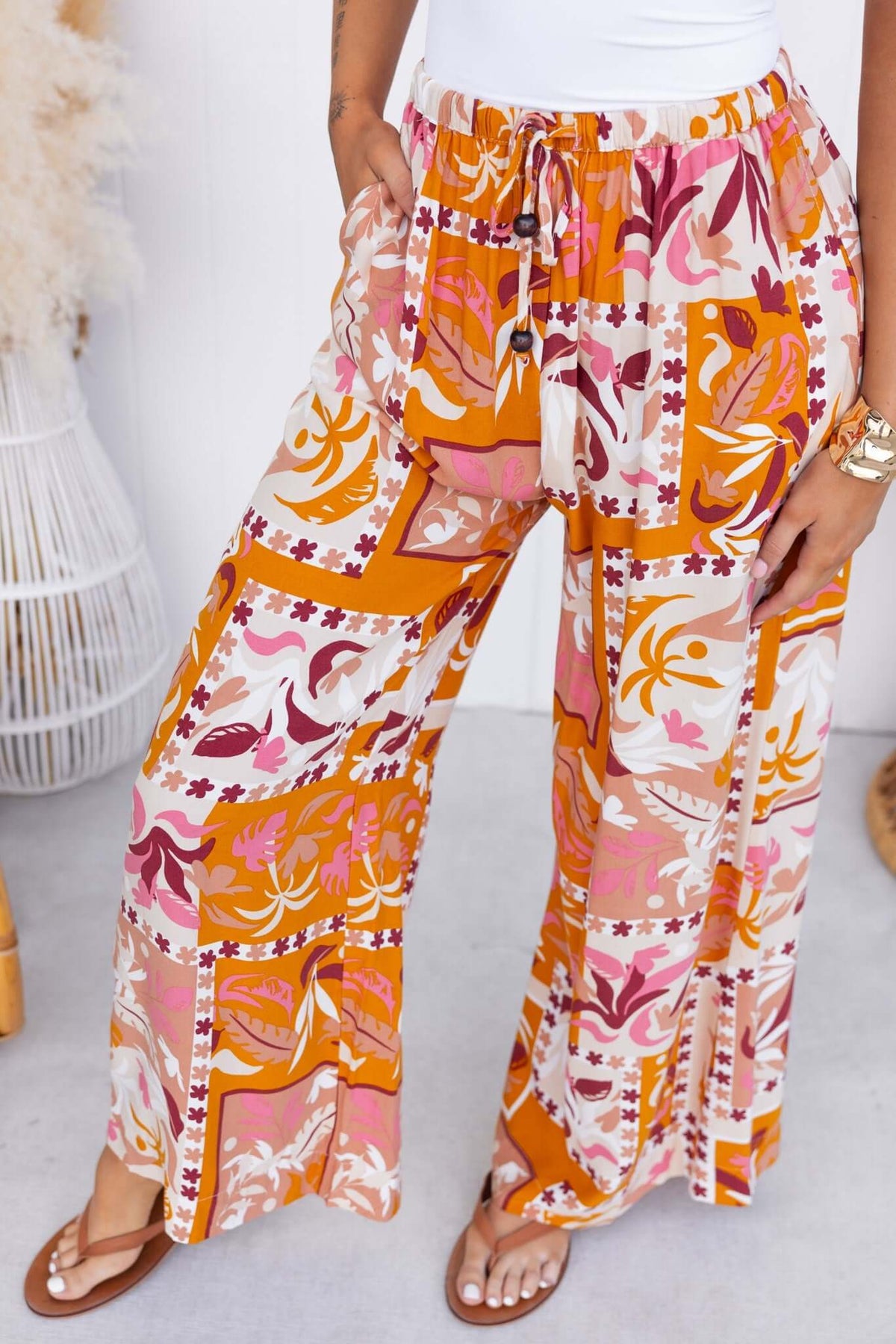 Valora Pants featuring a mid-high waist, elastic waistband, and vibrant floral patterns in orange and pink.