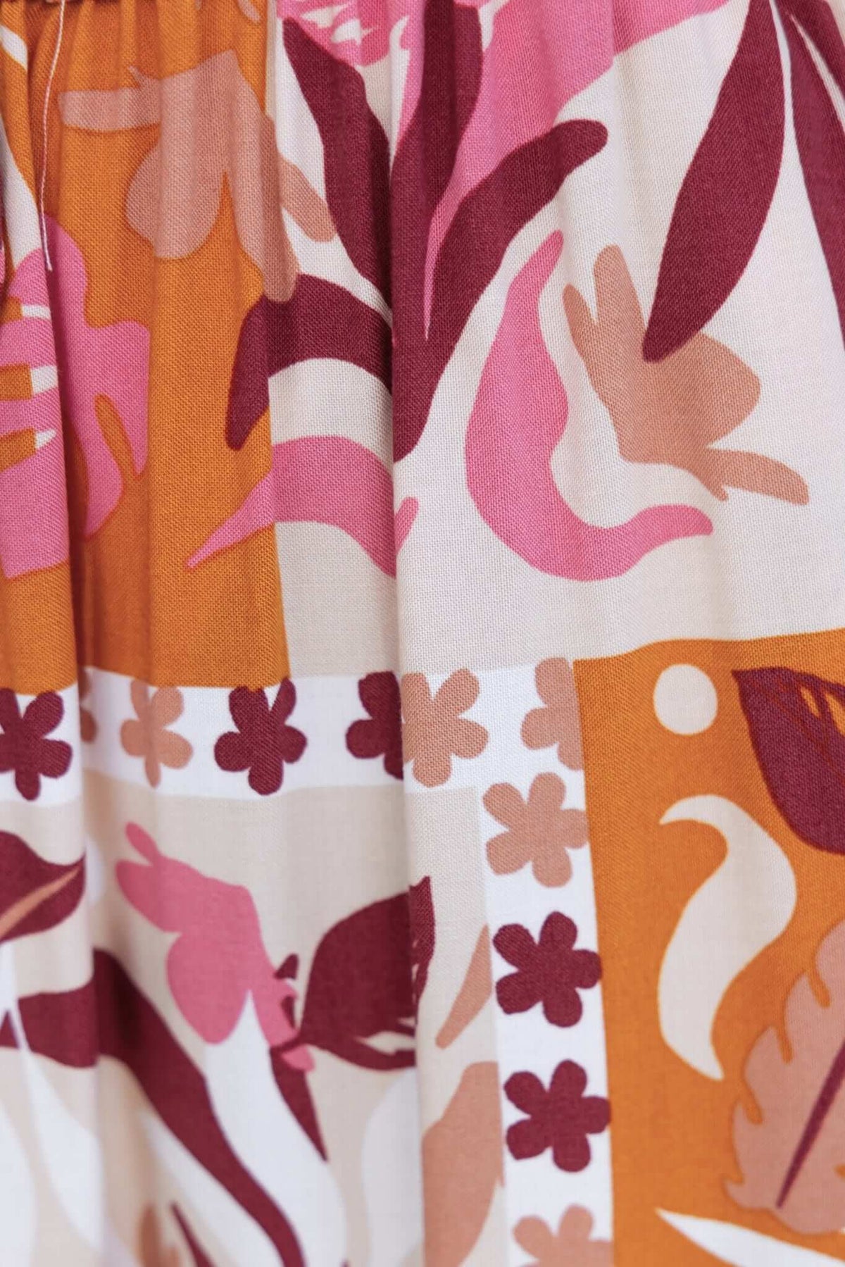 Colorful floral fabric pattern featuring shades of pink, orange, and maroon, ideal for stylish pants.
