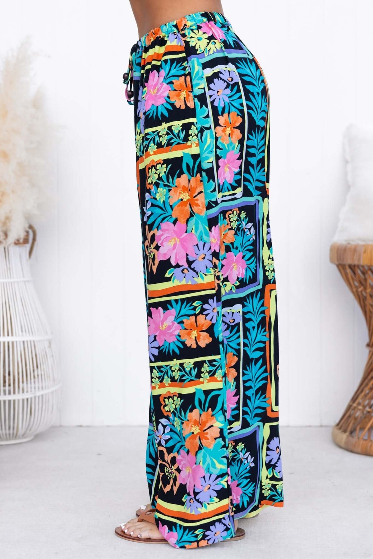 Delray Pants featuring colorful floral design, mid-high waist, elastic waistband, and pockets for a stylish casual look.