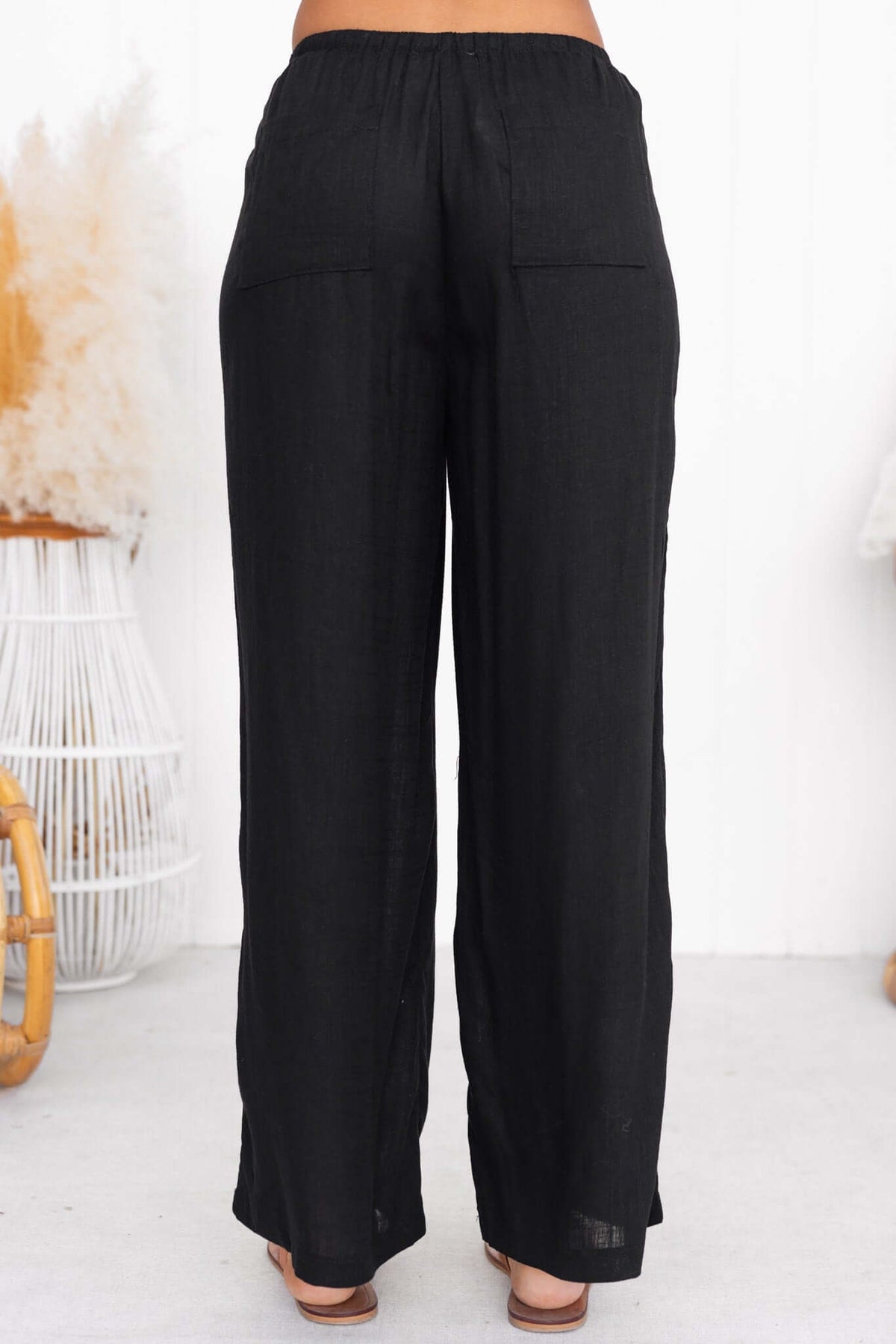 Irina Pants - Back view of black pants featuring an elastic waistband and pockets, made from 70% rayon and 30% linen.