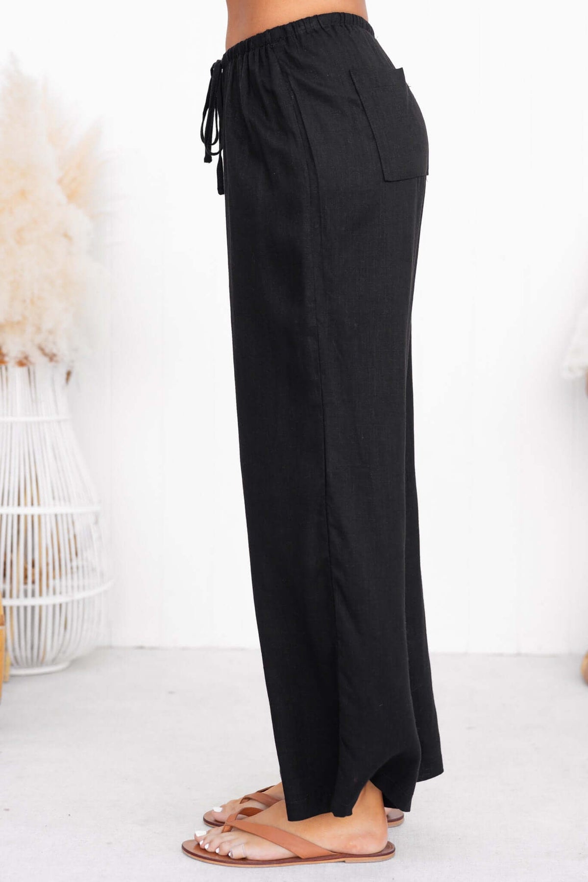 Side view of Irina Pants, black non-stretch trousers with drawstring waistband and back pocket.
