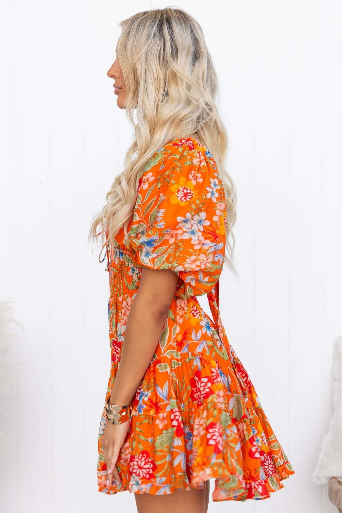 Airi Dress in vibrant orange floral pattern, featuring a V-neckline, puff sleeves, and a flared skirt.