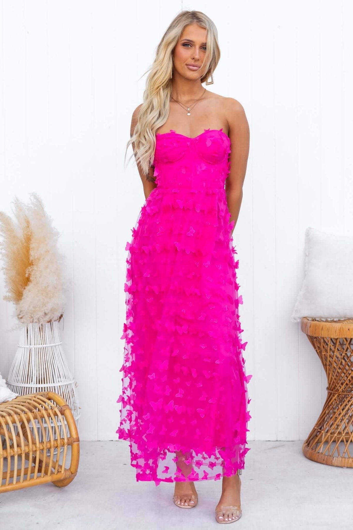 Model wearing a vibrant pink strapless Violette Maxi Dress with tulle material and floral details, showcased in a bright setting.