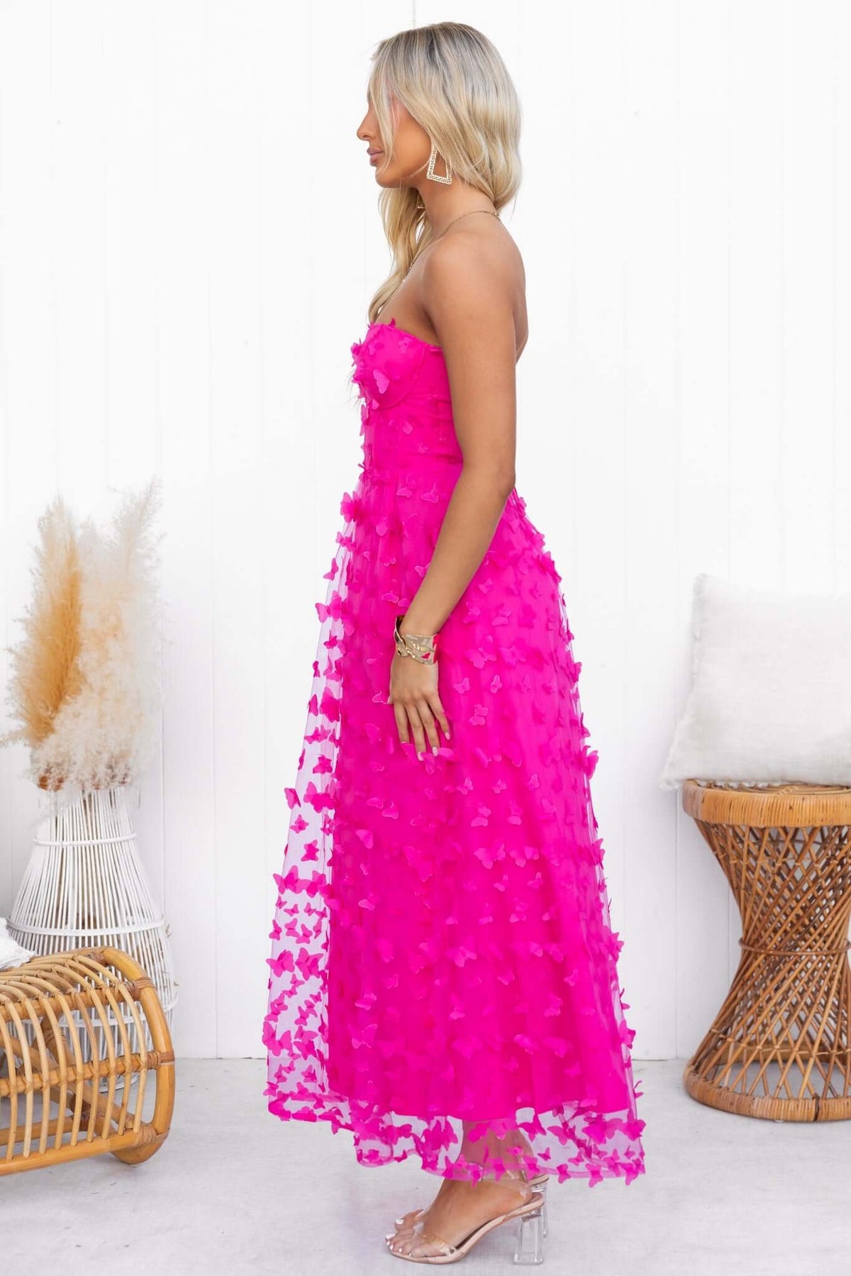 Profile view of a model wearing a bright pink strapless Violette Maxi Dress with floral tulle detailing.