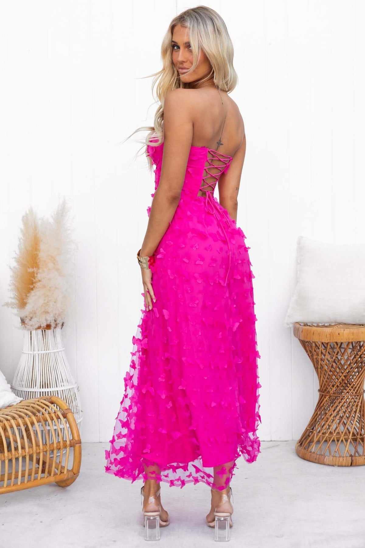 Back view of a model wearing a pink Violette maxi dress with tulle material and lace-up detail.