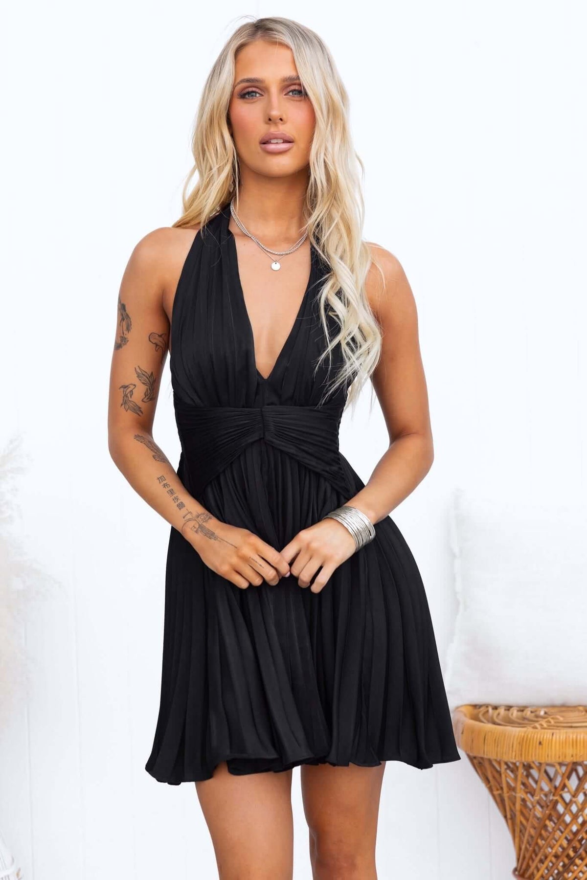 Model wearing a black special day dress with adjustable tie neckline and a pleated skirt.