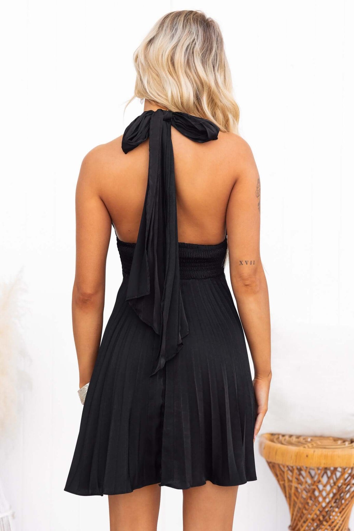 Back view of a black special day dress featuring an adjustable tie neckline and pleated skirt.