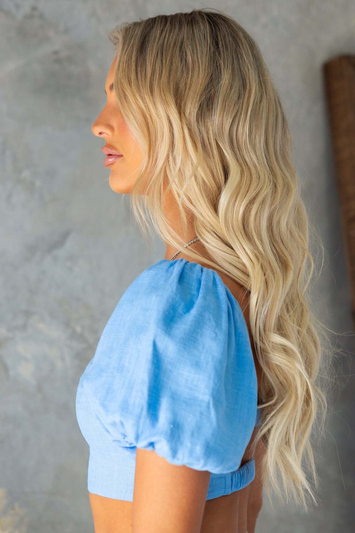 Side view of a model in a blue linen top featuring puff sleeves and a stylish design.