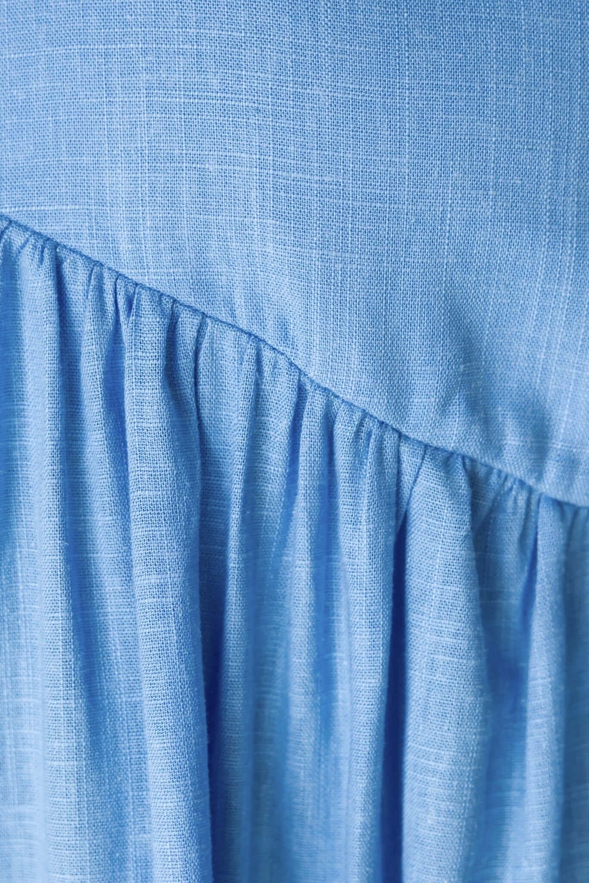 Close-up of light blue fabric showcasing gathered texture and linen-like appearance, perfect for feminine tops.