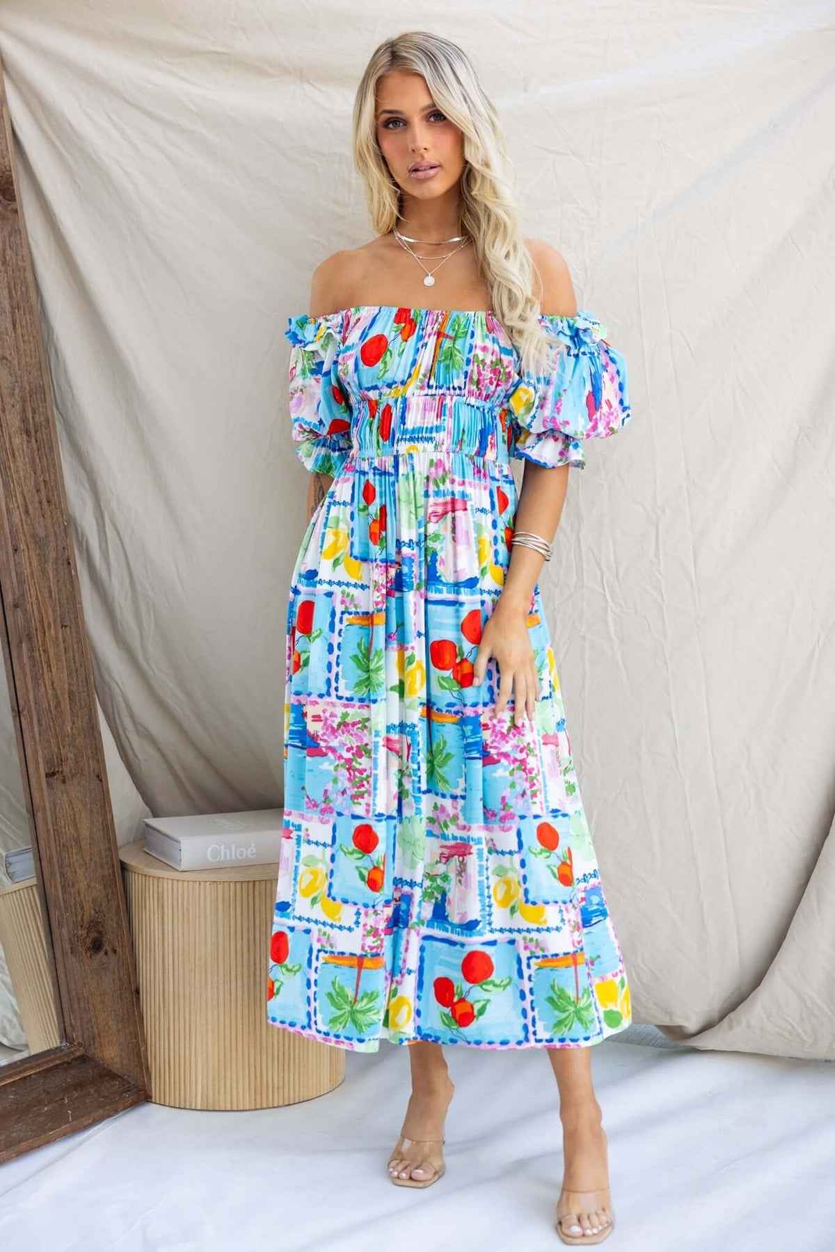 Dewberry Maxi Dress featuring off-shoulder neckline, colorful fruit print, and pockets, styled elegantly for summer.