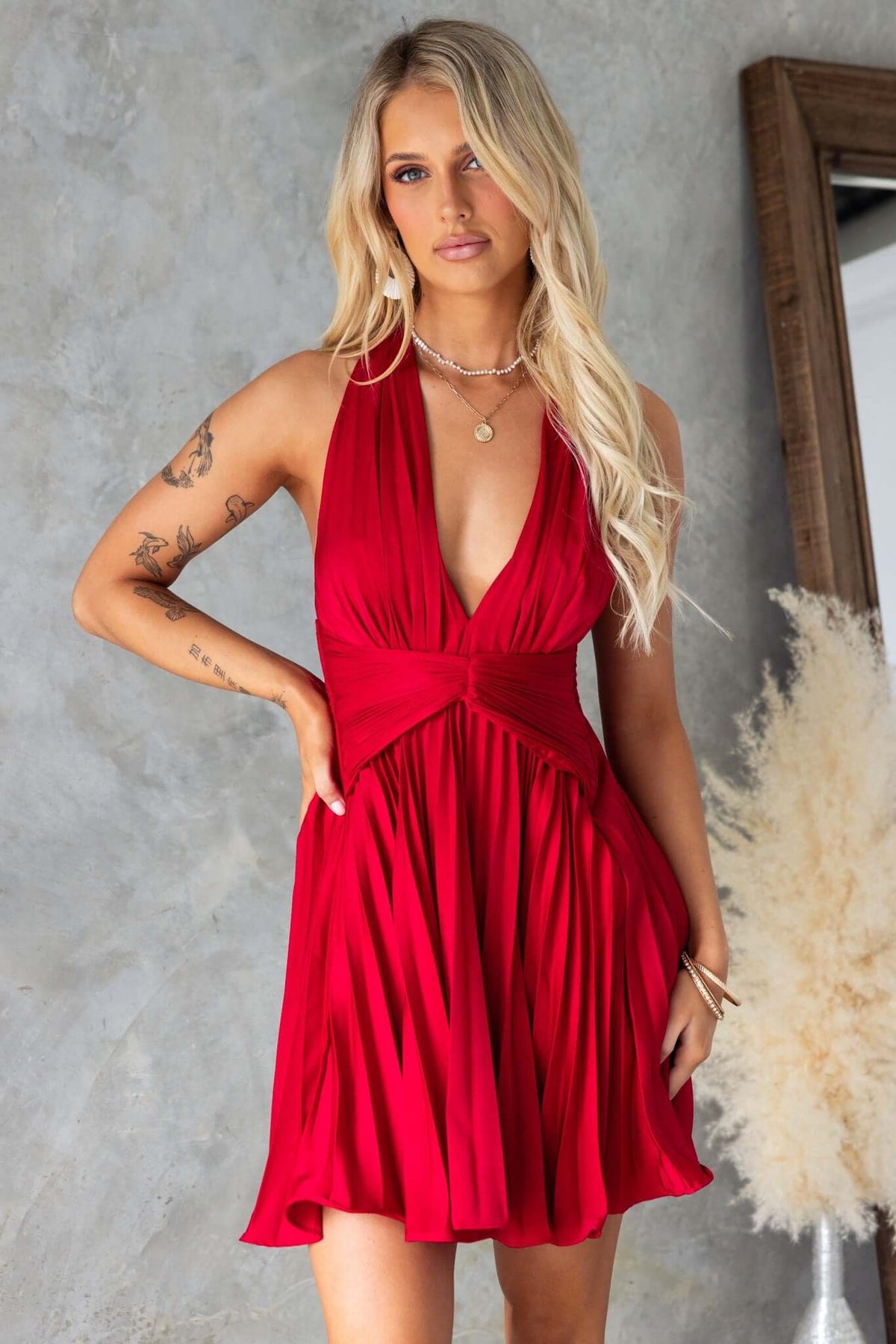 Vibrant red special day dress featuring adjustable tie neckline and pleated skirt, styled by a model in a chic setting.