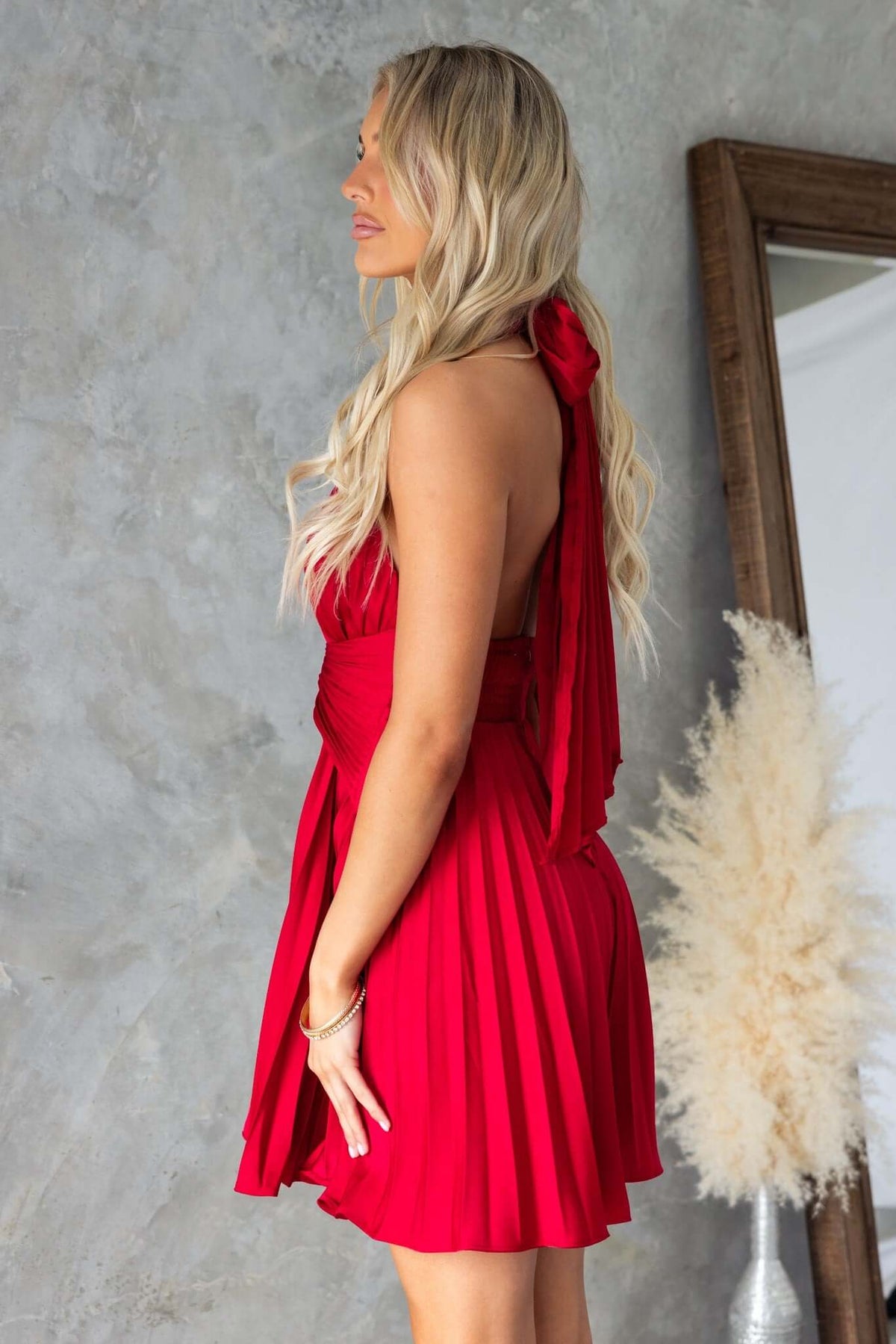 Model showcasing a red Special Day Dress with adjustable tie neckline and pleated design, perfect for formal occasions.