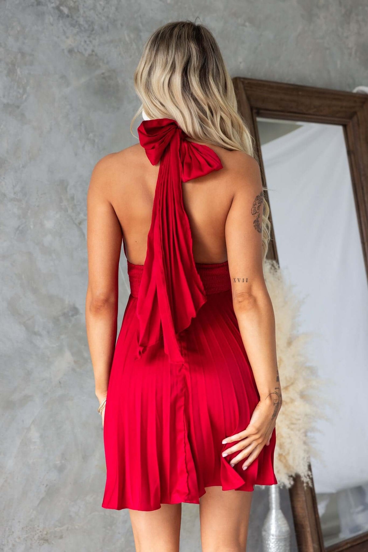 Back view of a red special day dress featuring an adjustable tie neckline and pleated skirt.