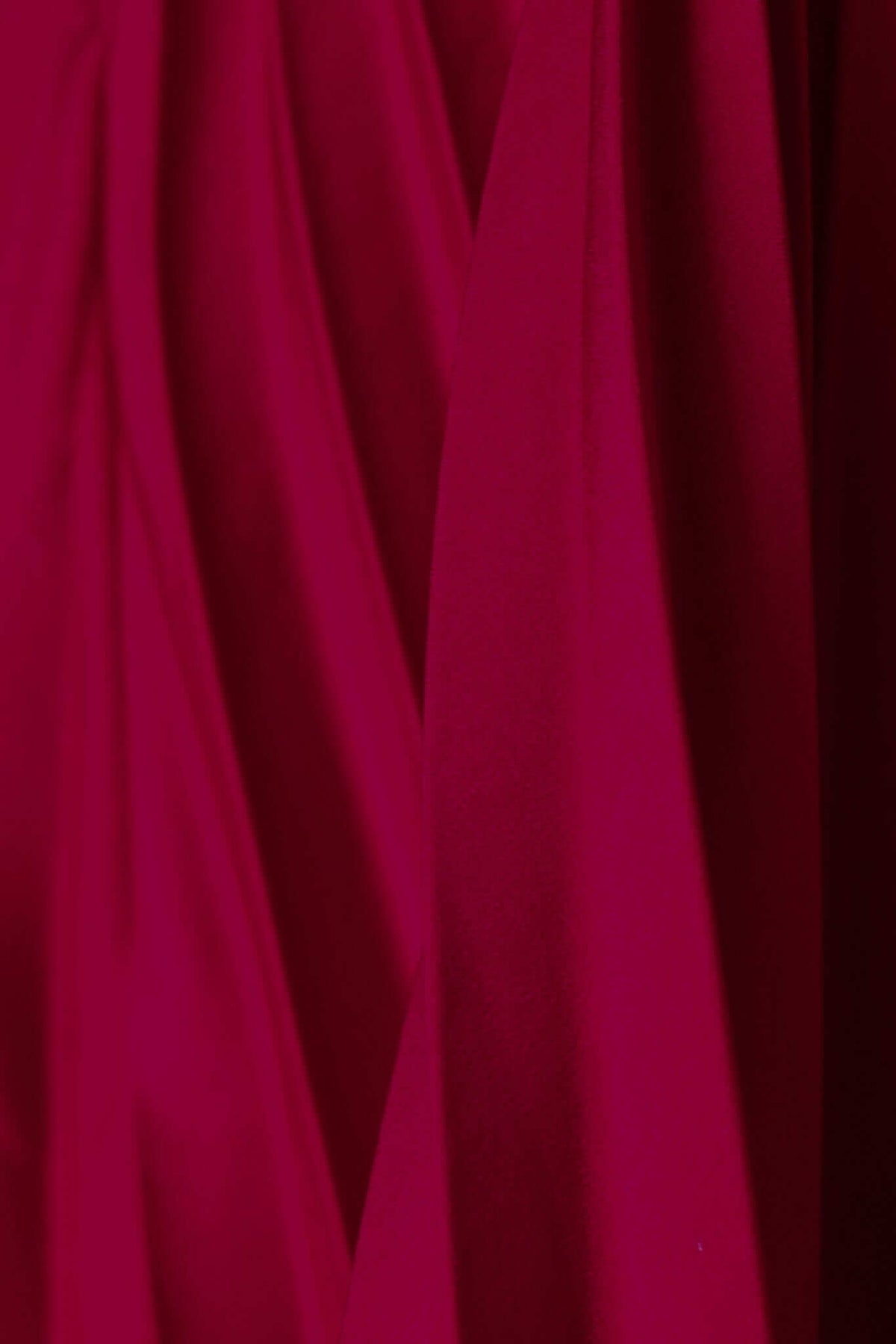 Close-up of rich red fabric with elegant draping, showcasing the satin look and feel for a special day dress.