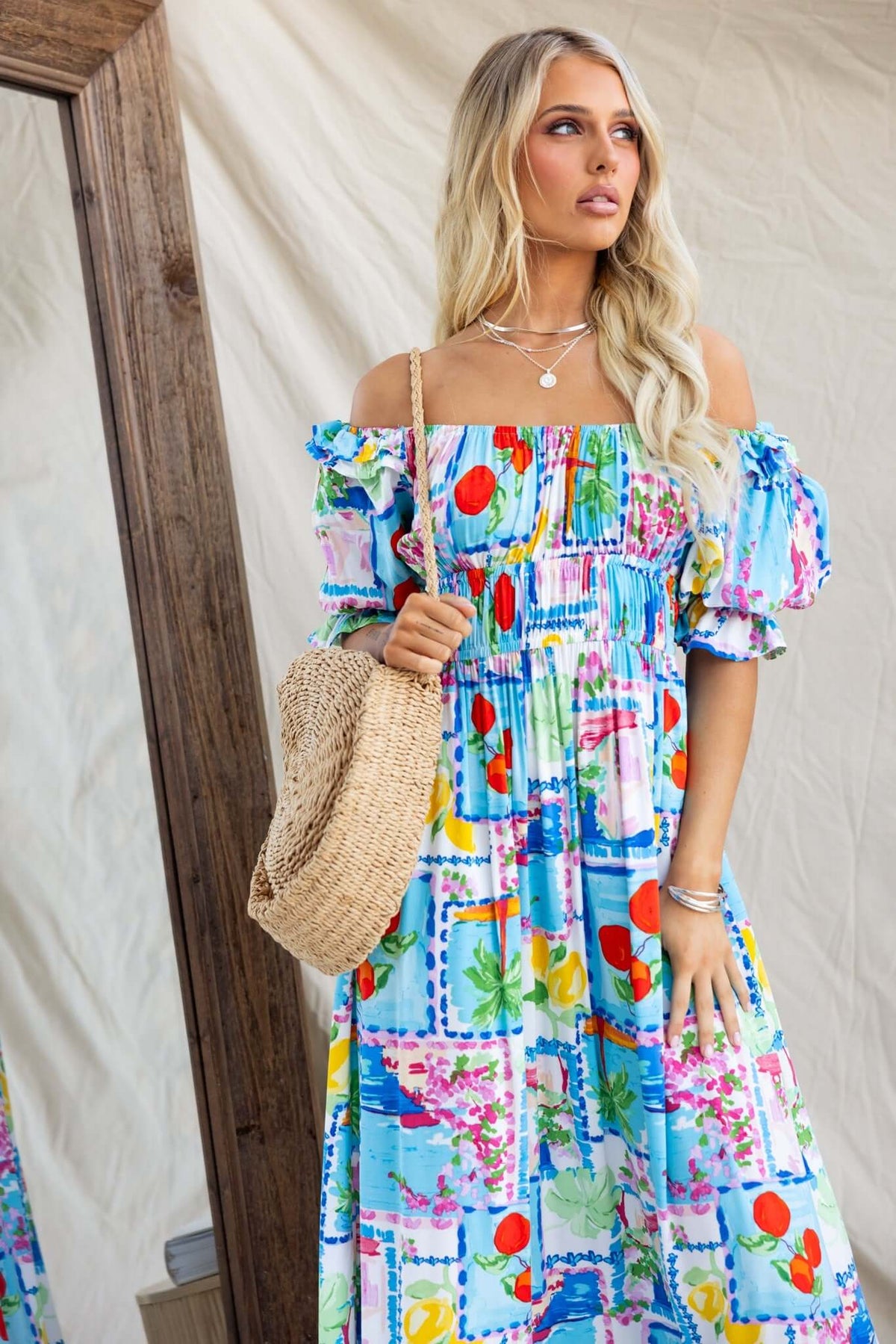 Dewberry Maxi Dress with off-shoulder neckline, colorful print, and pockets, styled with a chic bag.