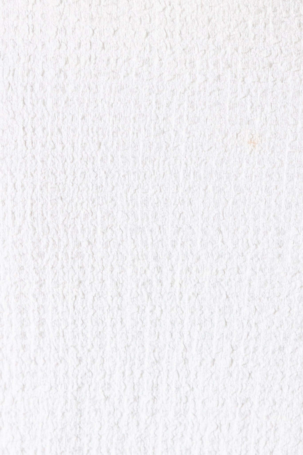 Close-up of textured white fabric, showcasing its soft and stretchable material ideal for clothing.