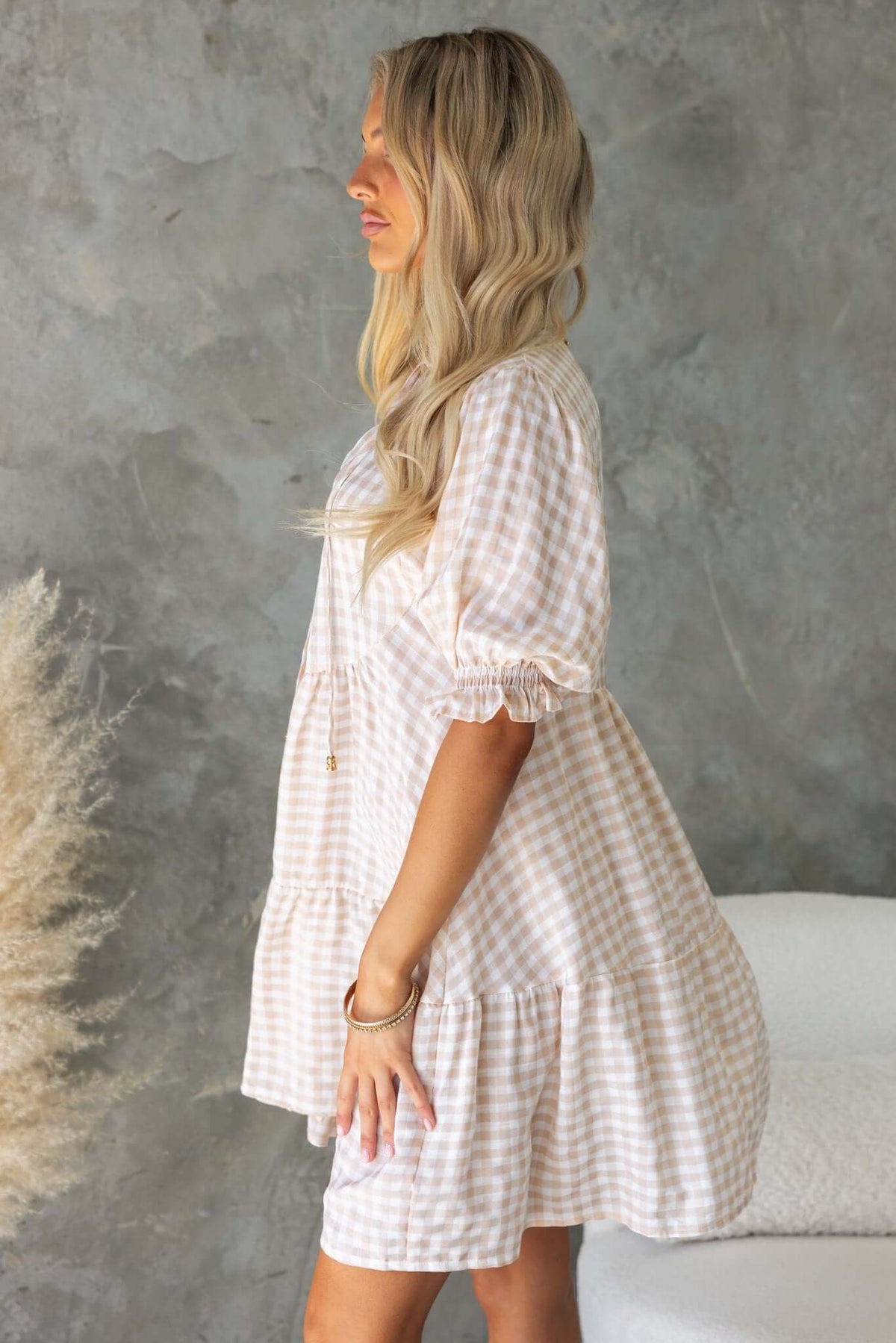 Side view of the Swinton Dress featuring a tie neckline, button-up front, and elastic sleeves in a stylish check pattern.