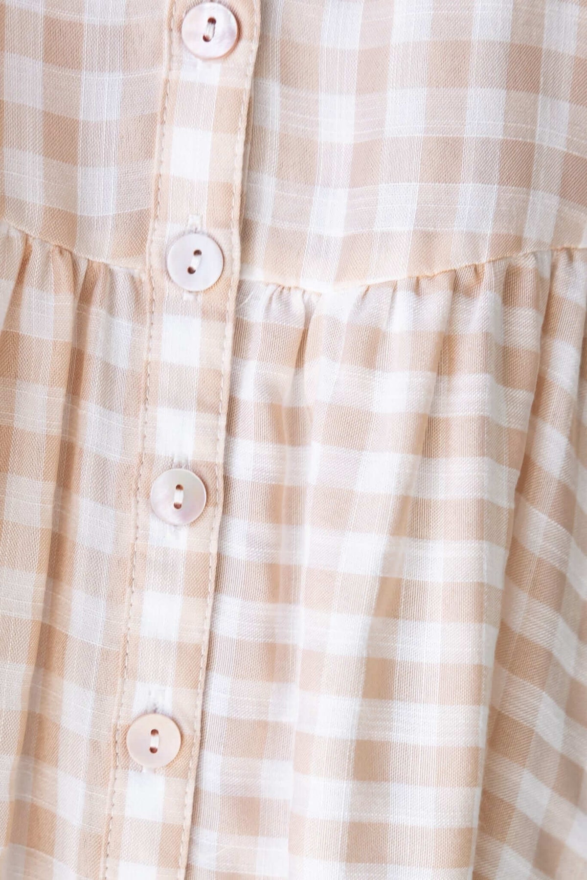 Close-up of Swinton Dress showing button-up front and patterned fabric in soft beige and white check.