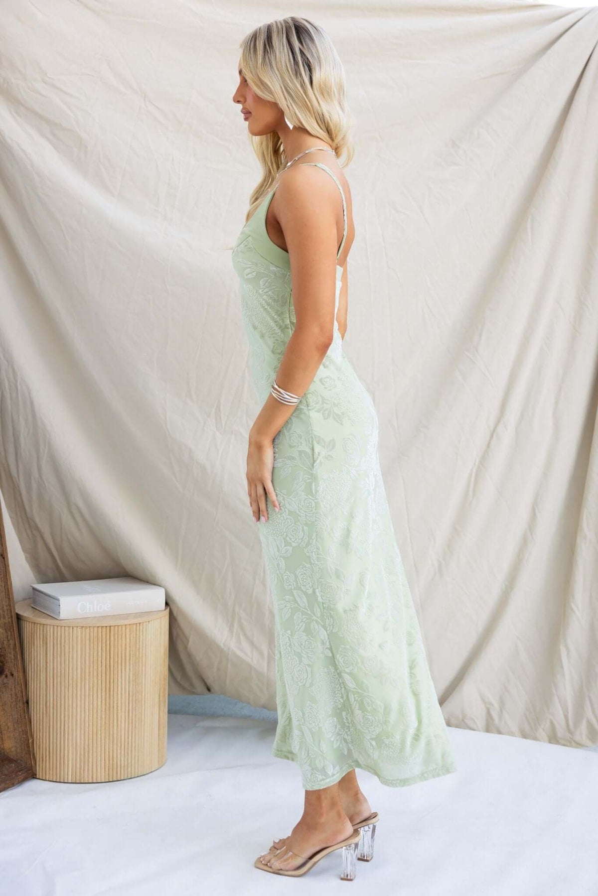 Side view of a model wearing a mint green Melita Maxi Dress with adjustable straps and embossed velvet print.