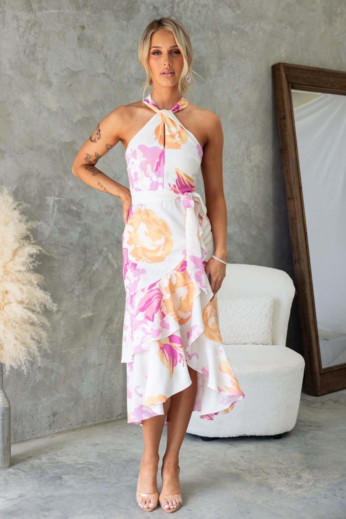 Model wearing Faiza Midi Dress with floral print and asymmetric hem, showcasing high neckline and removable tie.