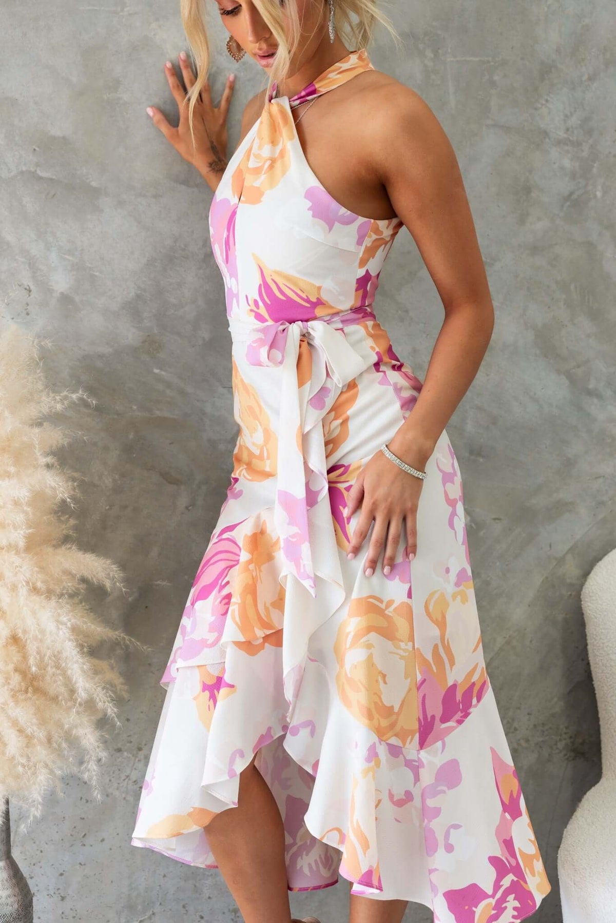 Model wearing Faiza Midi Dress featuring floral print, high neckline, asymmetrical hem, and removable tie detail.
