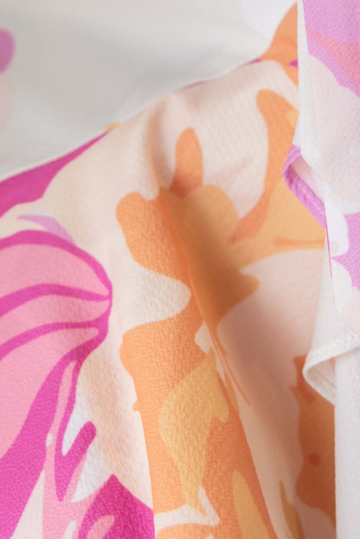 Close-up of floral fabric in soft pink and orange hues, highlighting the texture of the Faiza Midi Dress.