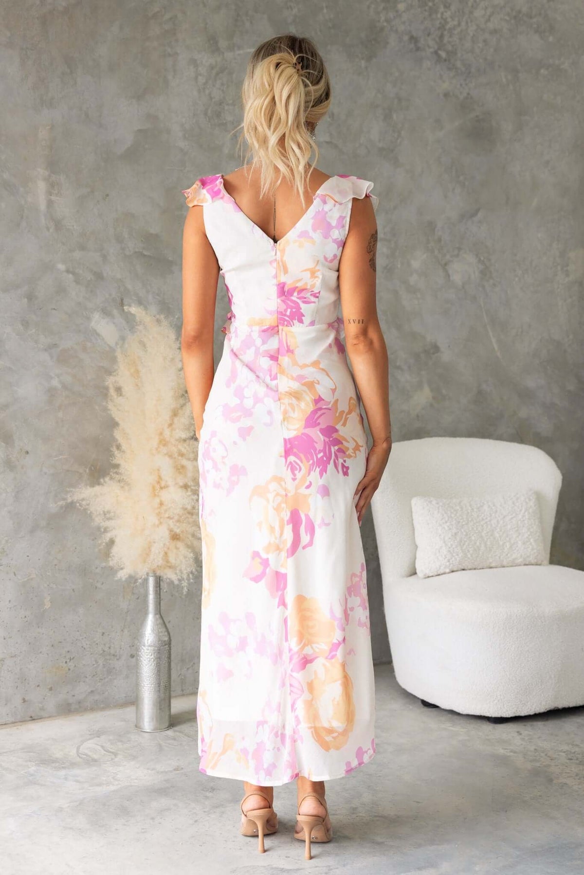 Back view of Bonnet Maxi Dress featuring ruffle details, V-neckline, and floral chiffon material.