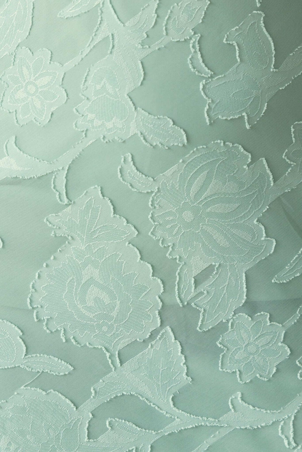 Close-up of textured floral embroidery on light green fabric, perfect for a stylish maxi dress.