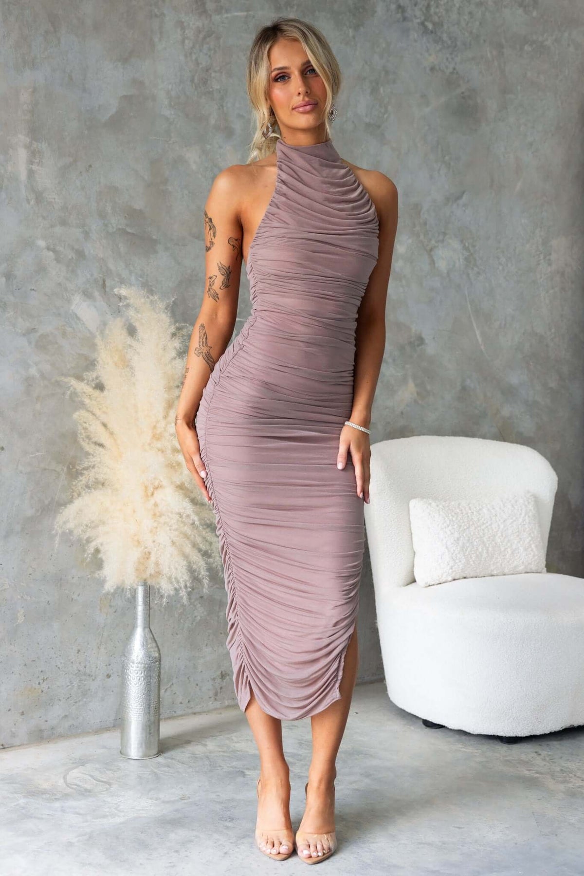 Gellis Midi Dress in mauve, featuring high neckline, ruching details, and asymmetric hemline, styled with minimal accessories.
