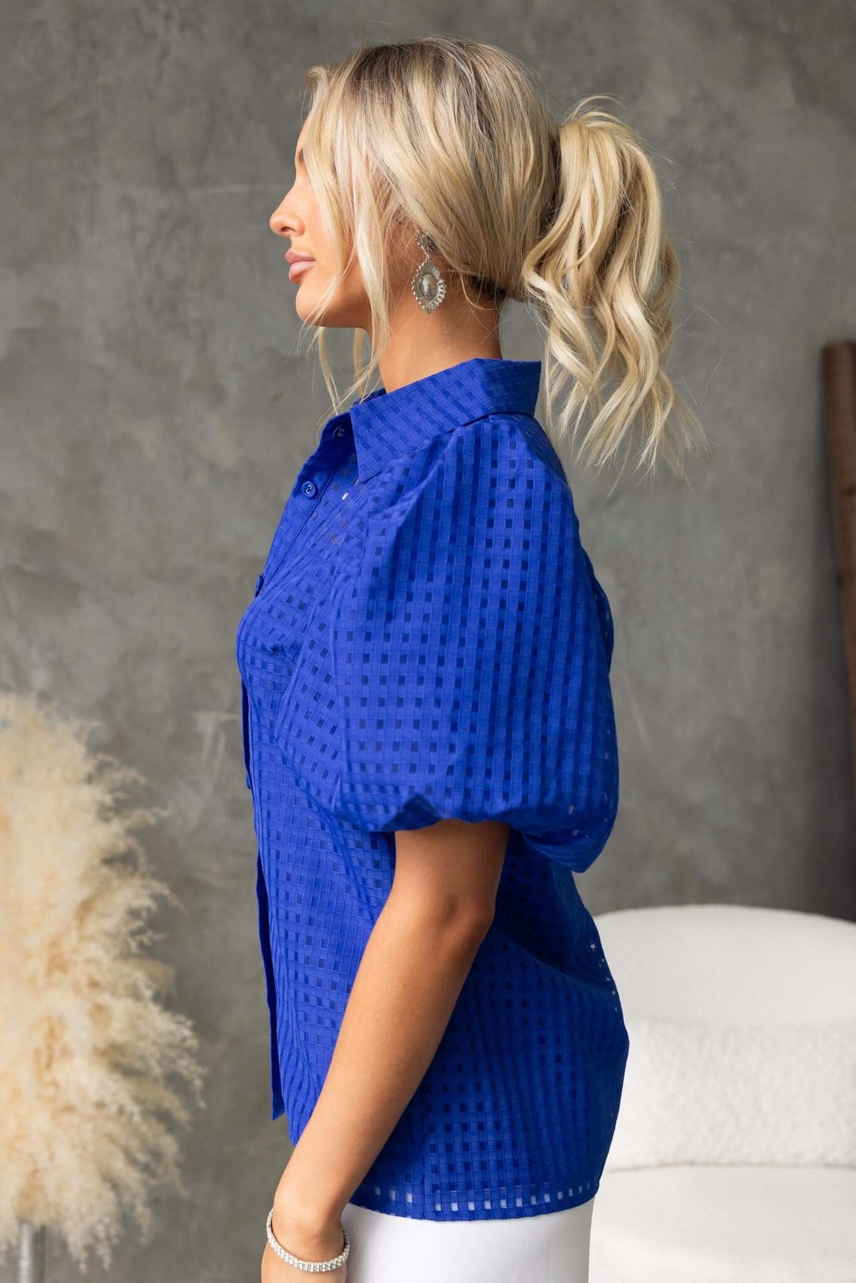 Side view of a woman wearing a blue Ursa Shirt with a button-up front and textured material.