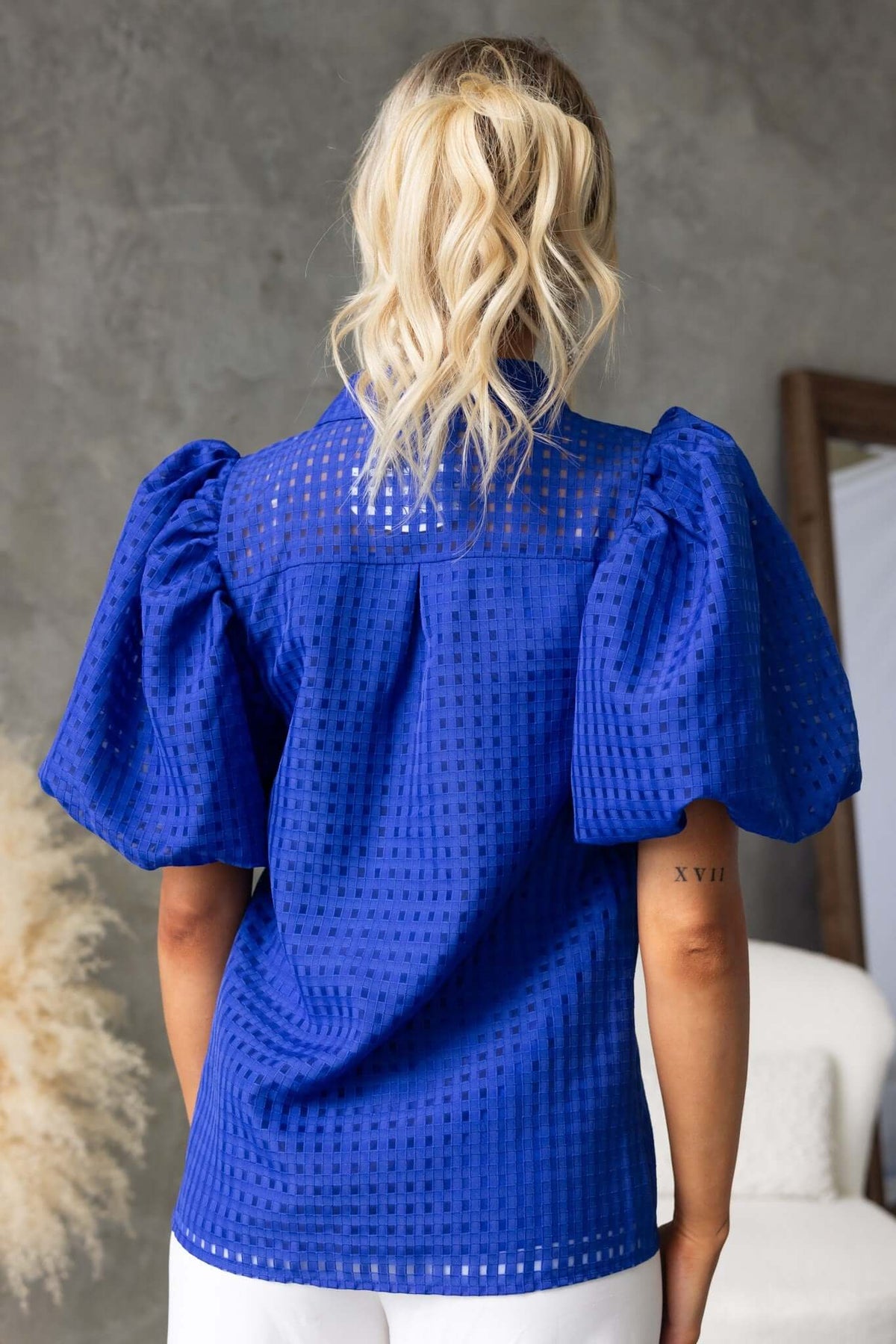 Back view of the Ursa Shirt, featuring a textured blue fabric and puff sleeves, perfect for stylish layering.