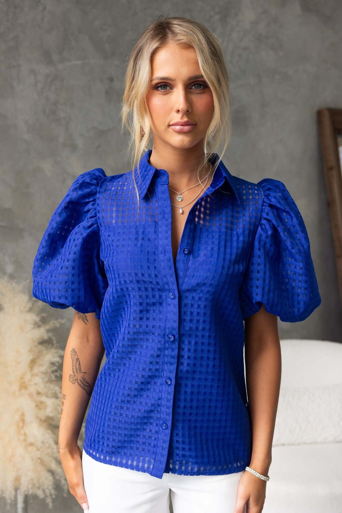 Model wearing a blue Ursa Shirt with puff sleeves and a button-up front, styled for a chic casual look.