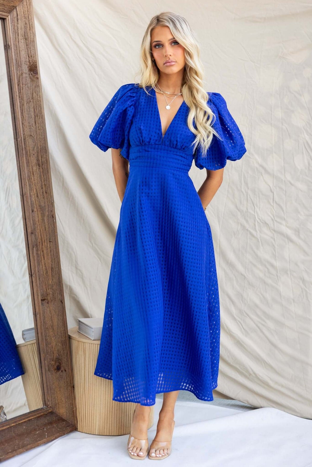 Nosita Midi Dress in vibrant blue, featuring a V-neckline, puff sleeves, and textured fabric with pockets.